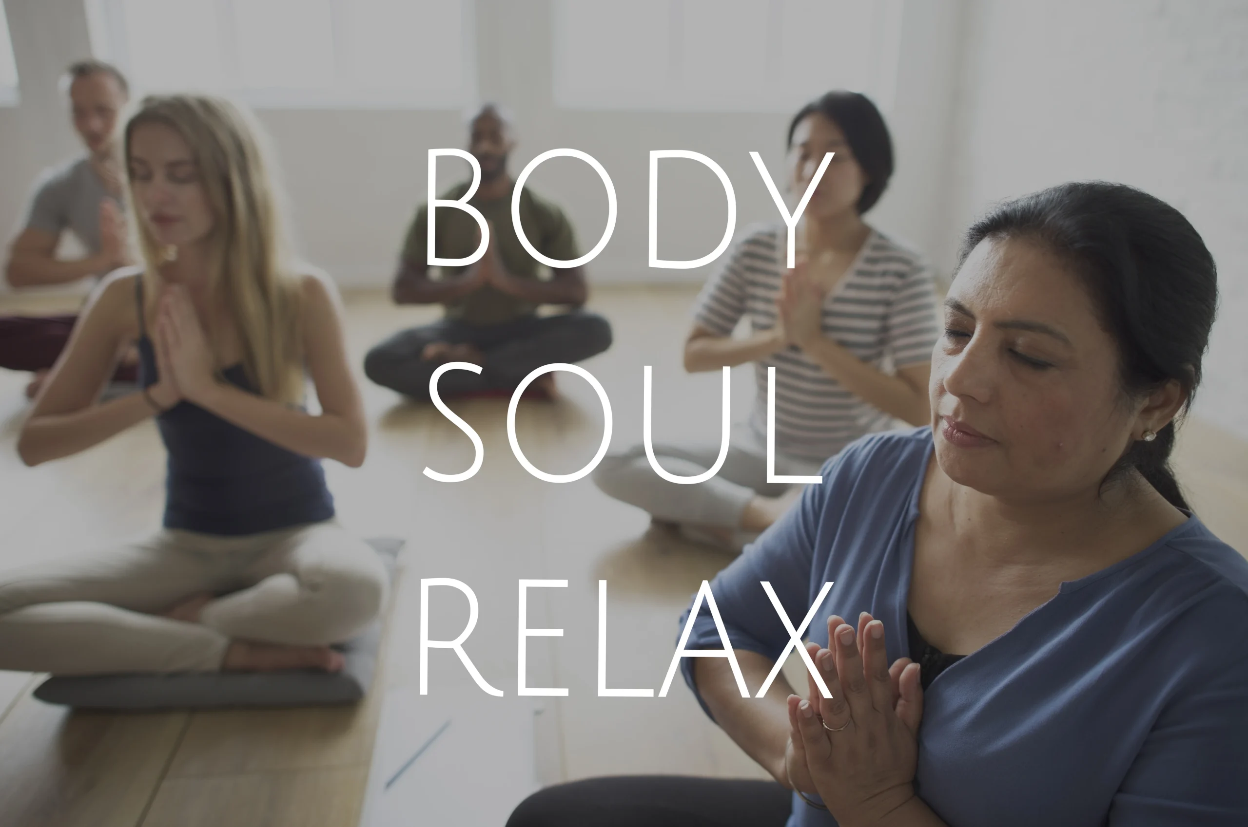 Holistic Wellbeing- Gemini said An group of diverse people sit on the floor in a bright, minimalist room, practicing meditation or yoga. They are seated in cross-legged positions with their eyes closed and hands held in a prayer position. The image has a soft, slightly desaturated filter. Large, white sans-serif text is centered over the image, reading: BODY SOUL RELAX