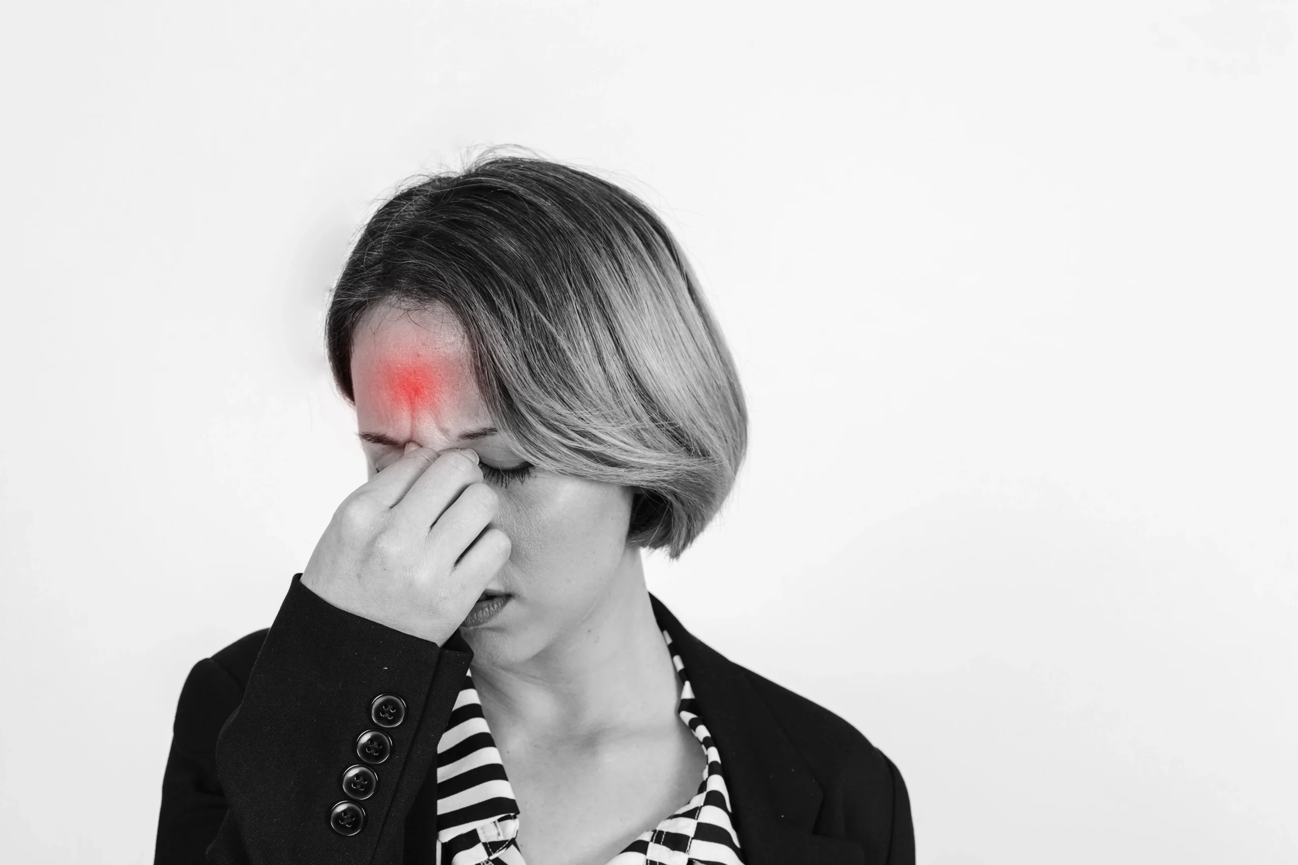 A woman holding the bridge of her nose with closed eyes, showing discomfort and pressure in the forehead area, symbolizing sinusitis, sinus pain, and nasal congestion.